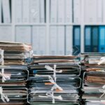 Stacks of files and paperwork in the office and bookshelves on the background: management and storage concept