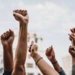 People with raised fists at a demonstration in the city. Multi-ethnic group of people together on strike.