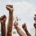 People with raised fists at a demonstration in the city. Multi-ethnic group of people together on strike.