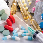 Syringe, blisters with colorful pills and capsules. Medical equipment.