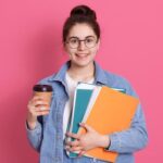 smiling-student-holding-books-coffee-cup-photo