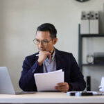 Serious executive businessman is busy with paperwork on the table in the office.