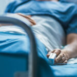 In the Hospital Sick Male Patient Sleeps on the Bed. Heart Rate Monitor Equipment is on His Finger.