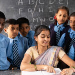 Teacher with students around explaining or teaching from book on classroom - concept of support, education, assistance and guidance.