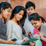Pretty Smiling Young Indian Students with Laptop and tablet computer Looking at Camera